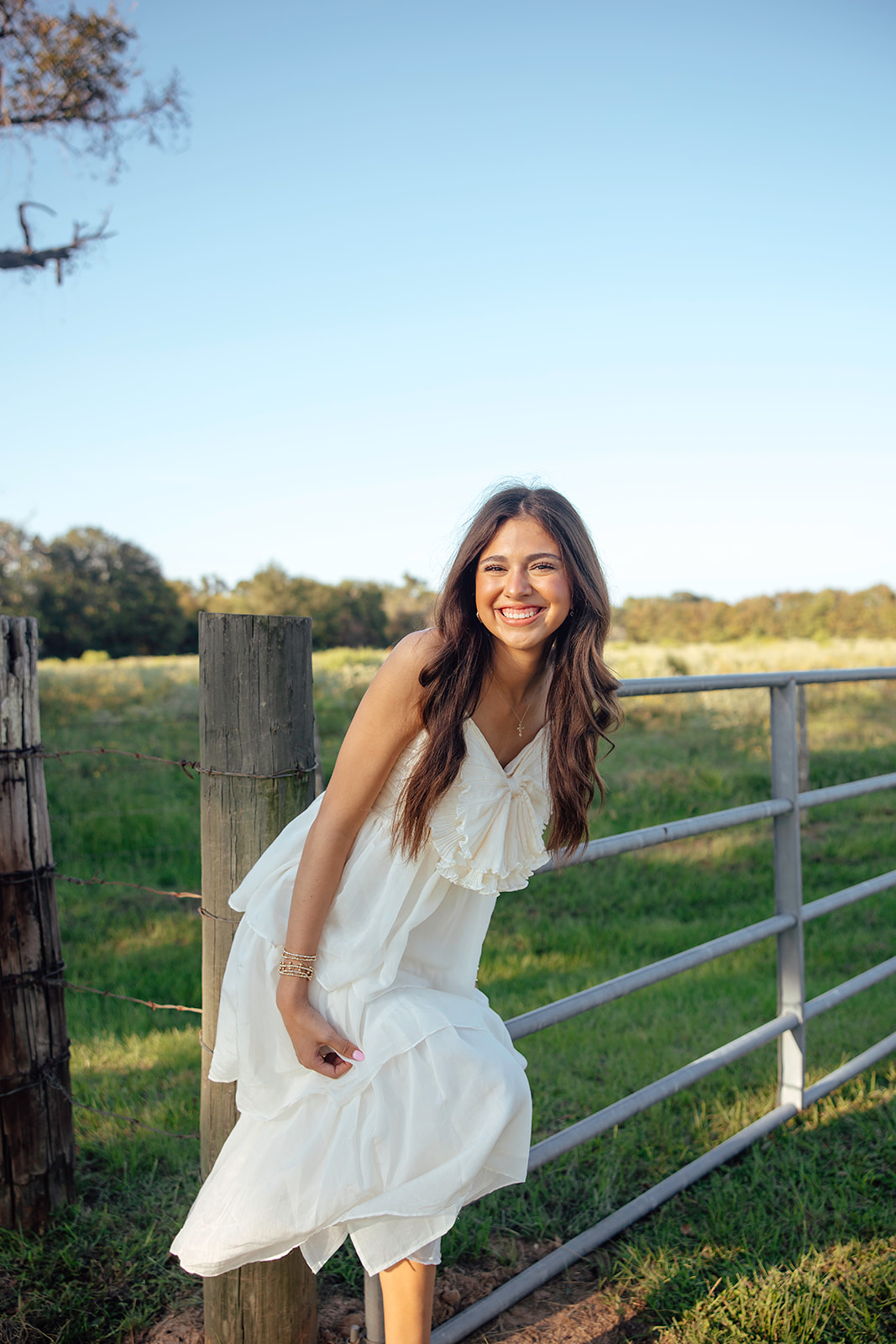 high school senior poses in a Texas field during her senior photo session with Kennedi Cooper Photography