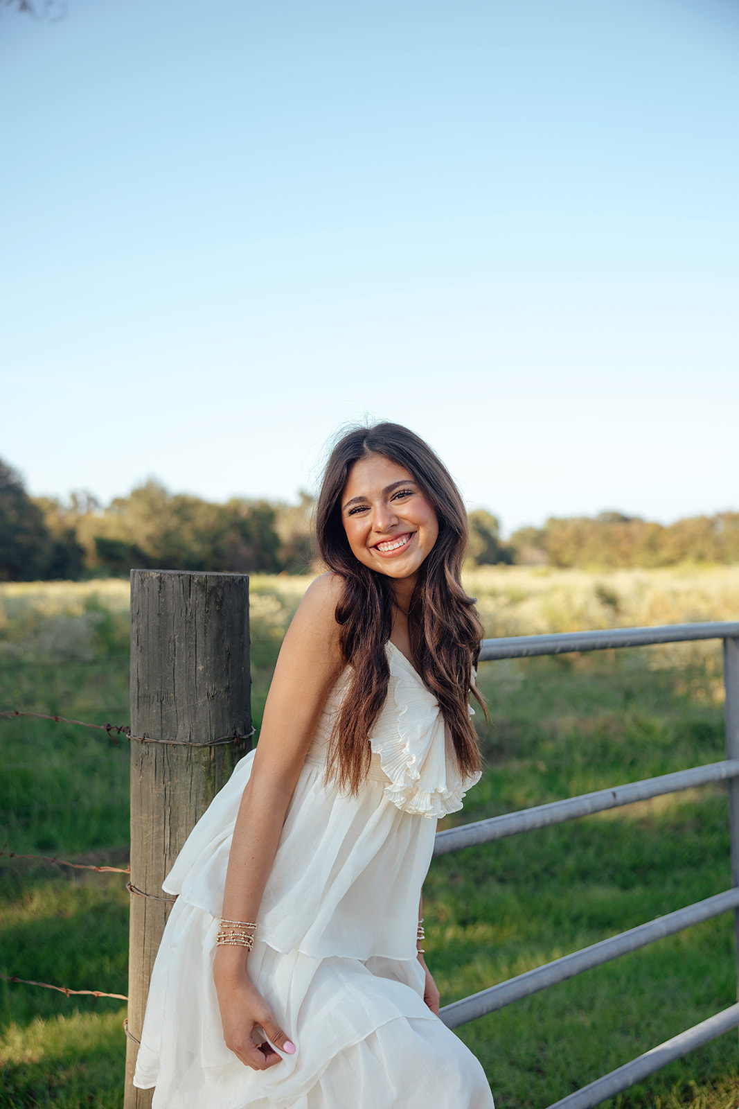 high school senior poses in a Texas field during her senior photo session with Kennedi Cooper Photography