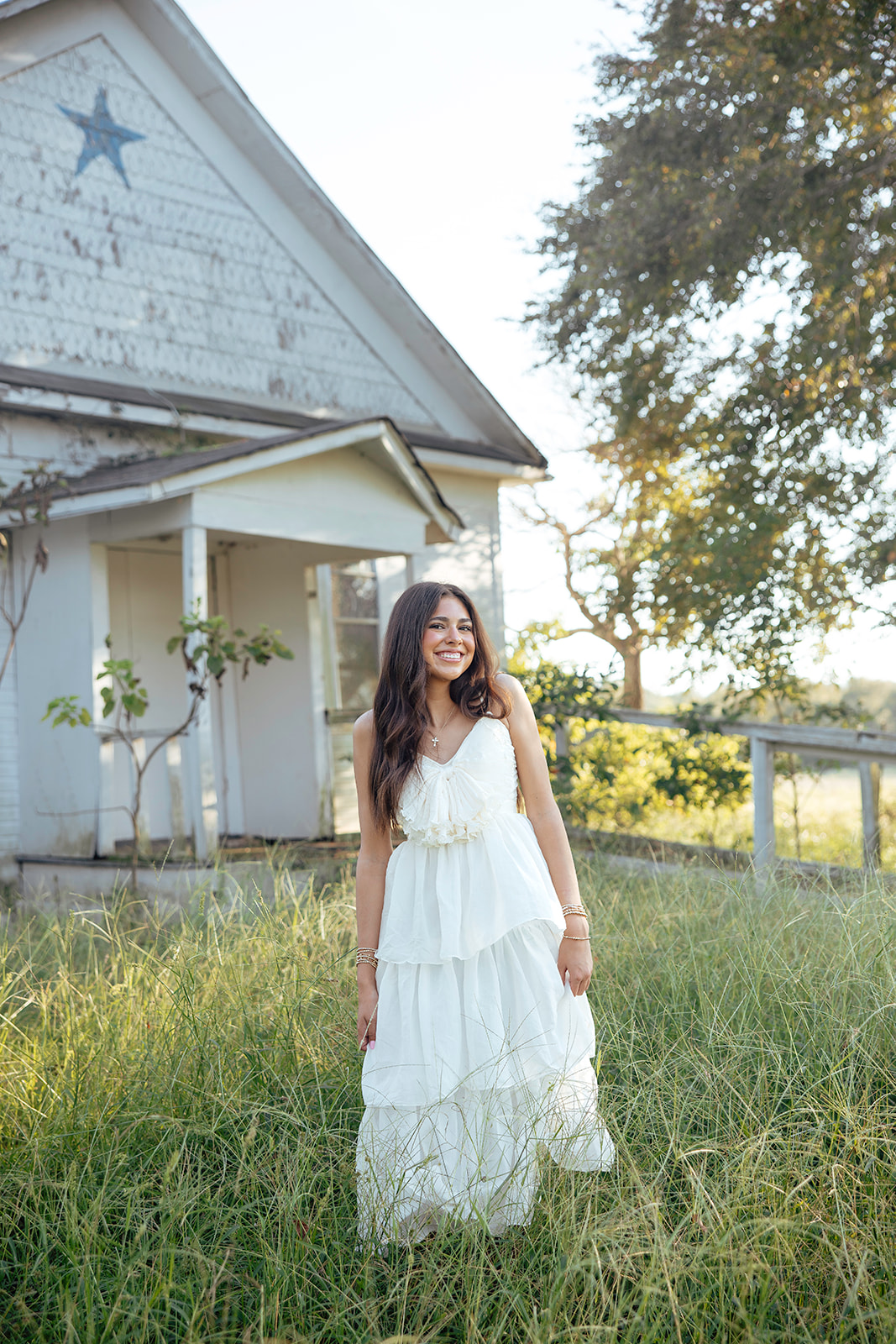 high school senior poses in a Texas field during her senior photo session with Kennedi Cooper Photography