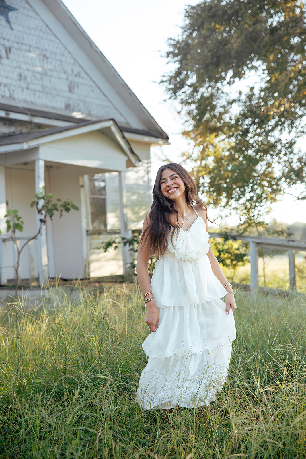 high school senior poses in a Texas field during her senior photo session with Kennedi Cooper Photography