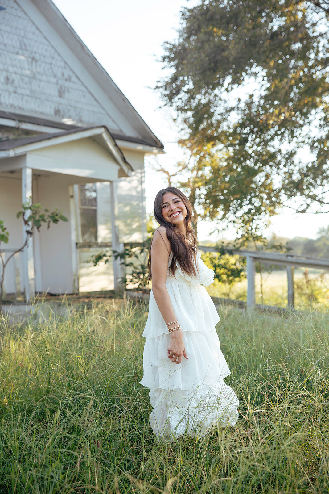 high school senior poses in a Texas field during her senior photo session with Kennedi Cooper Photography