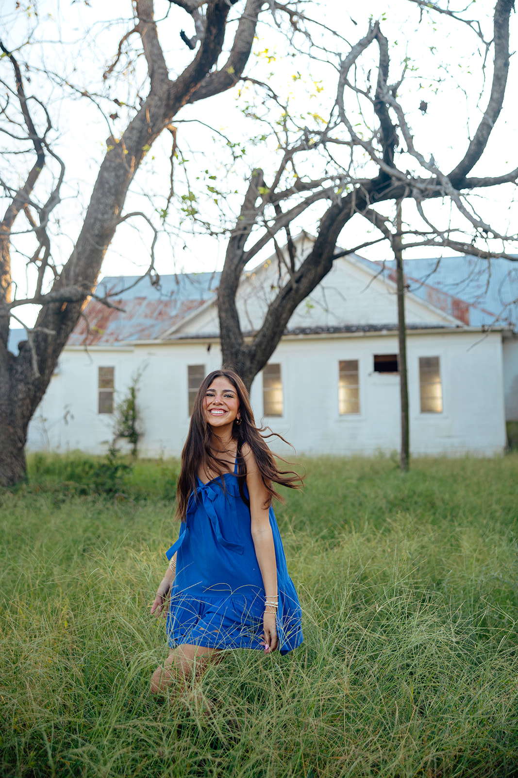 high school senior poses in a Texas field during her senior photo session with Kennedi Cooper Photography