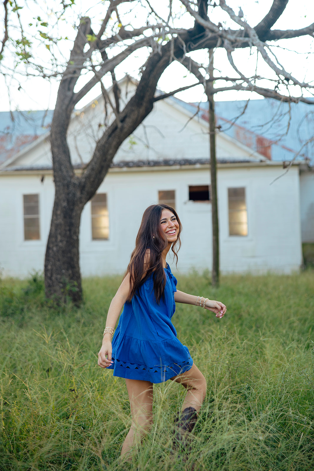 high school senior poses in a Texas field during her senior photo session with Kennedi Cooper Photography
