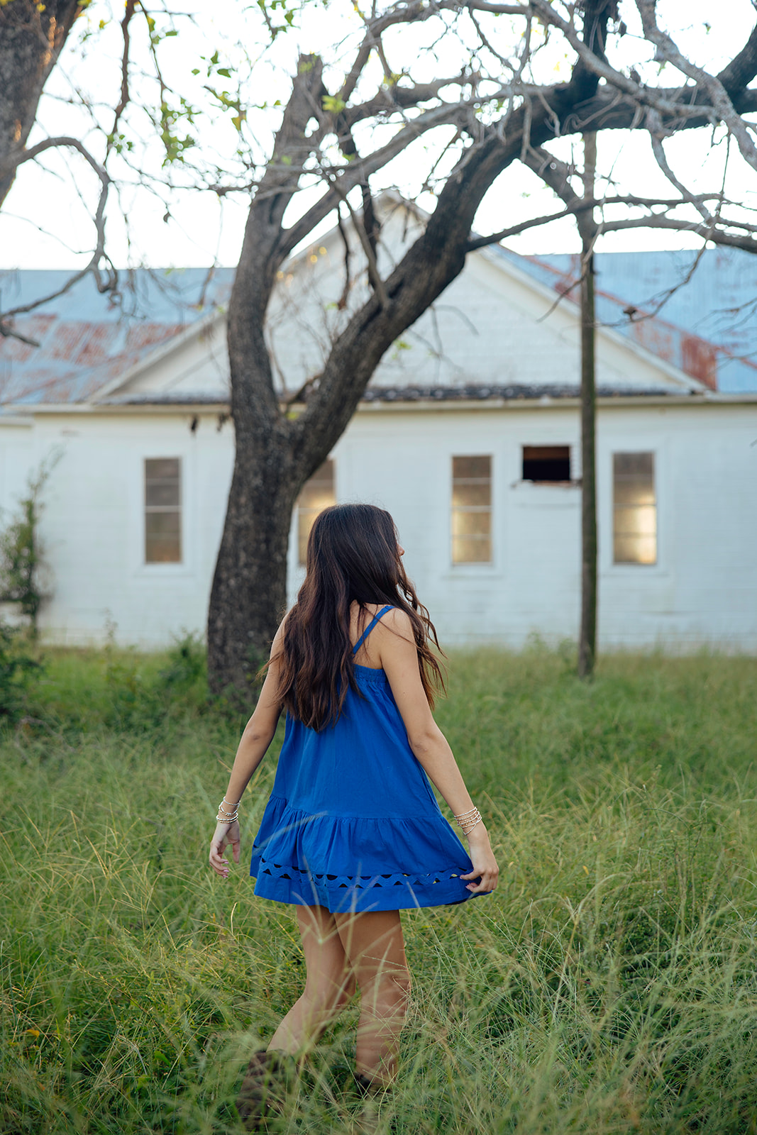 high school senior poses in a Texas field during her senior photo session with Kennedi Cooper Photography