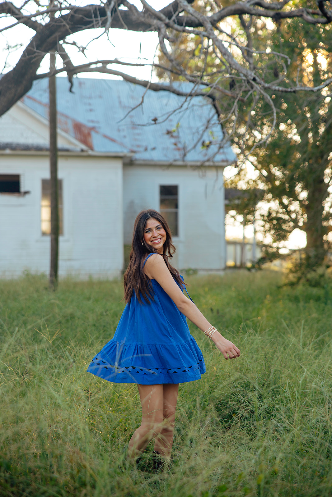 high school senior poses in a Texas field during her senior photo session with Kennedi Cooper Photography