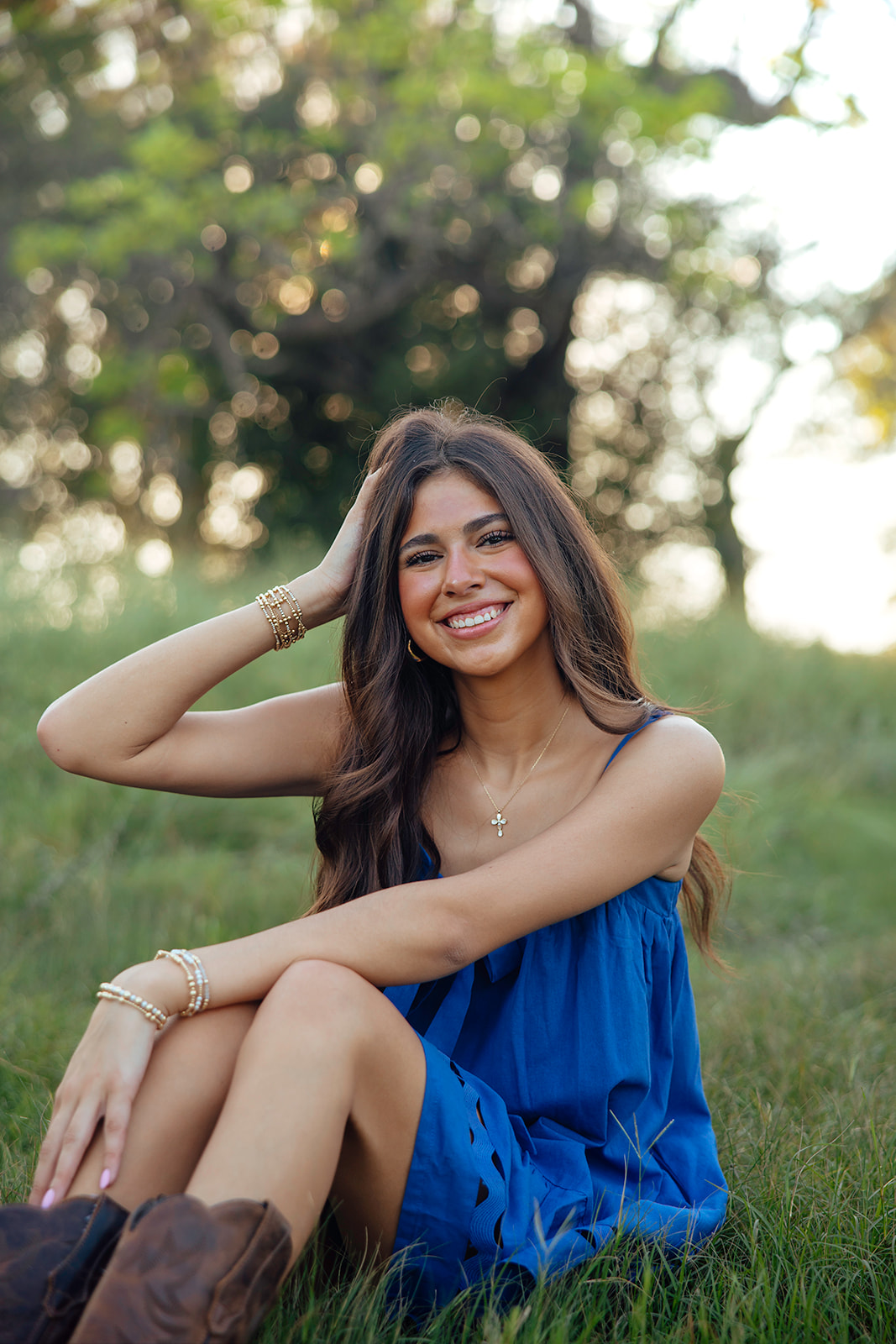 high school senior poses in a Texas field during her senior photo session with Kennedi Cooper Photography
