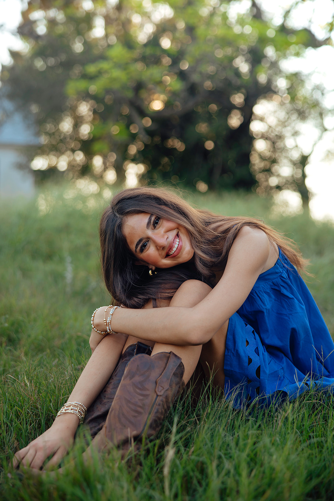 high school senior poses in a Texas field during her senior photo session with Kennedi Cooper Photography