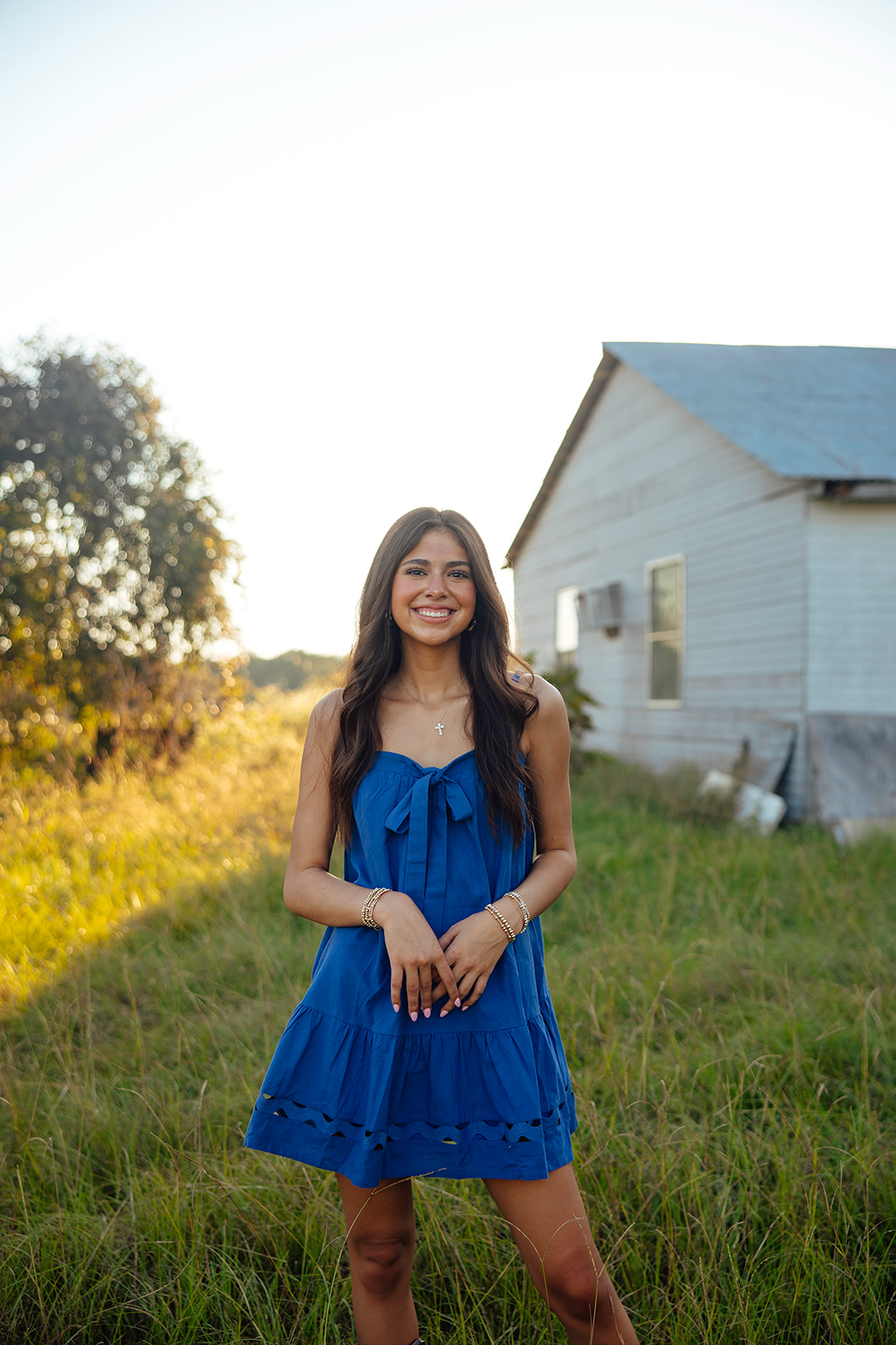 high school senior poses in a Texas field during her senior photo session with Kennedi Cooper Photography