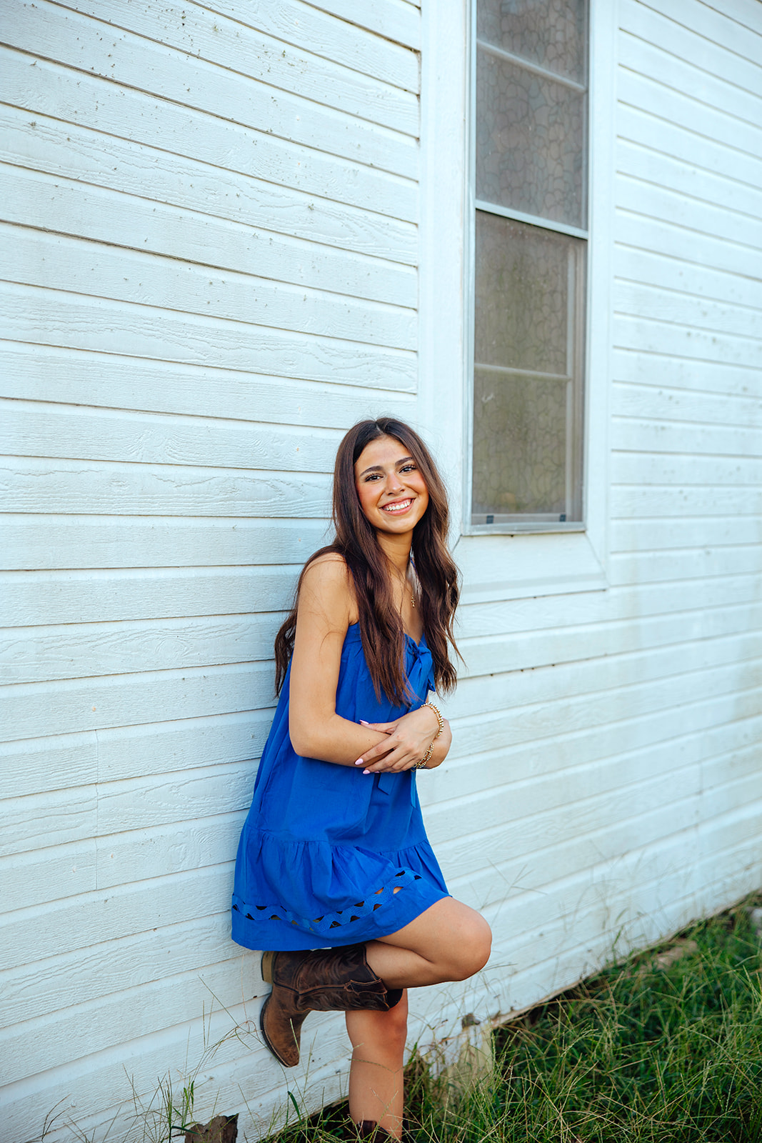 high school senior poses in a Texas field during her senior photo session with Kennedi Cooper Photography
