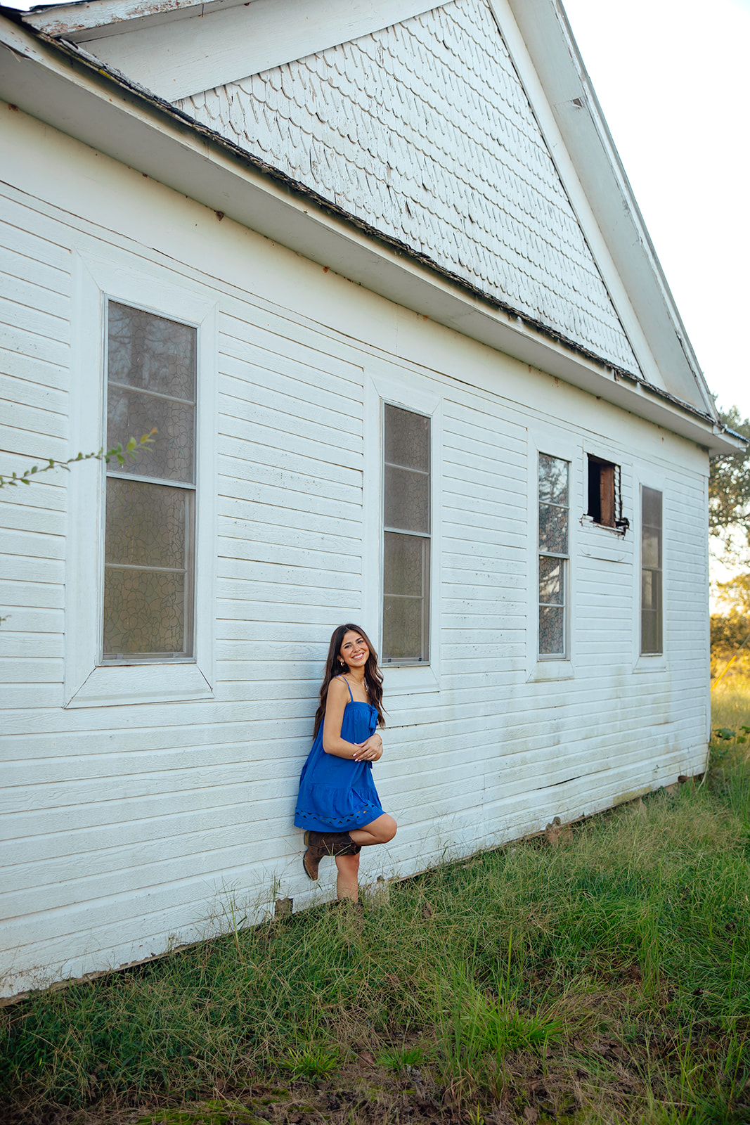 high school senior poses in a Texas field during her senior photo session with Kennedi Cooper Photography