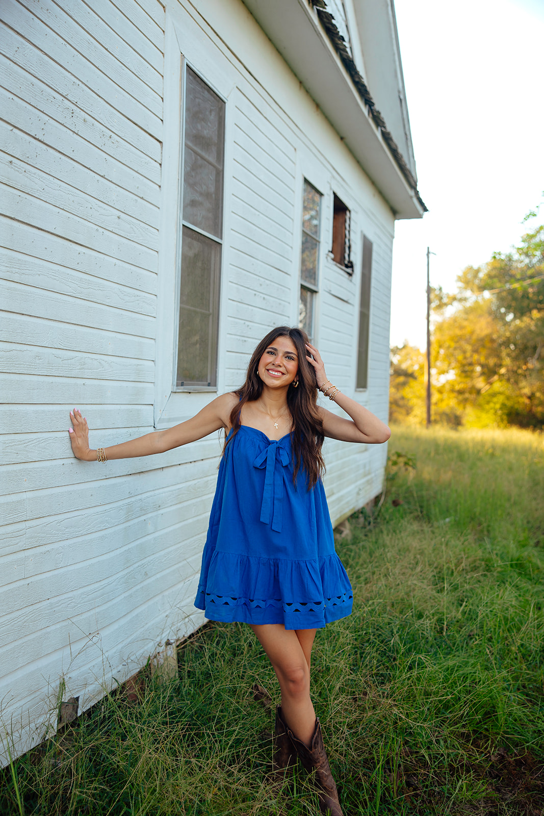 high school senior poses in a Texas field during her senior photo session with Kennedi Cooper Photography