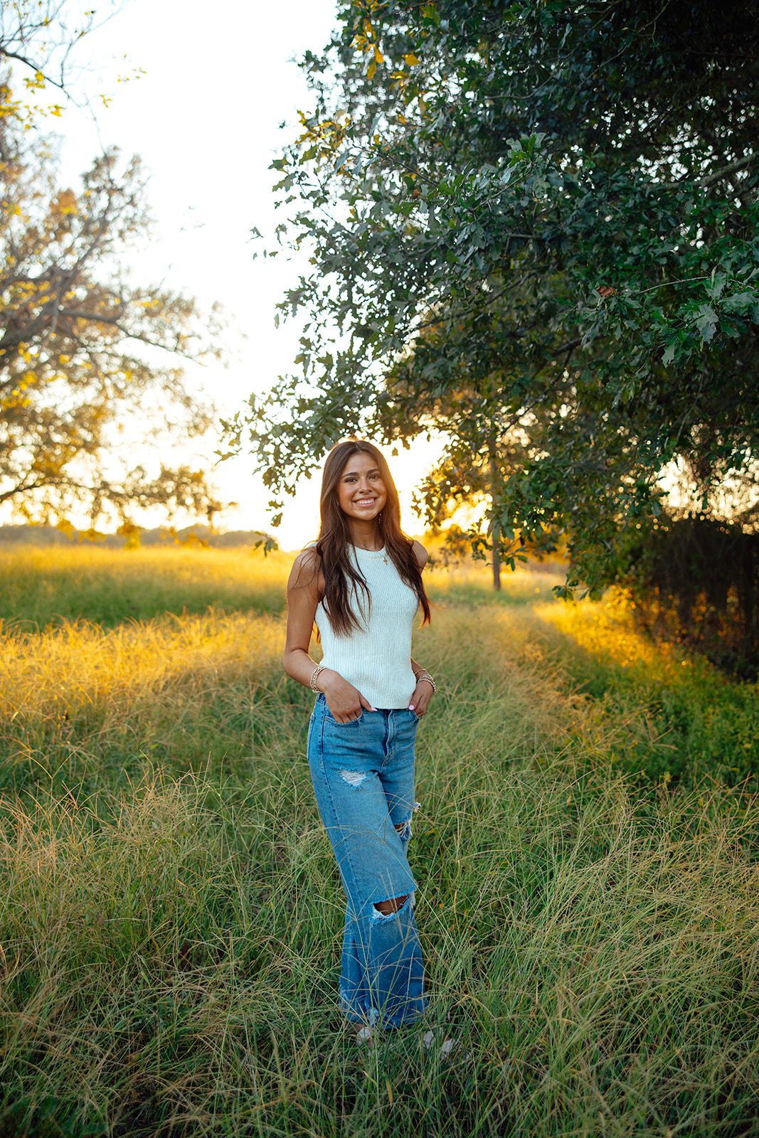high school senior poses in a Texas field during her senior photo session with Kennedi Cooper Photography