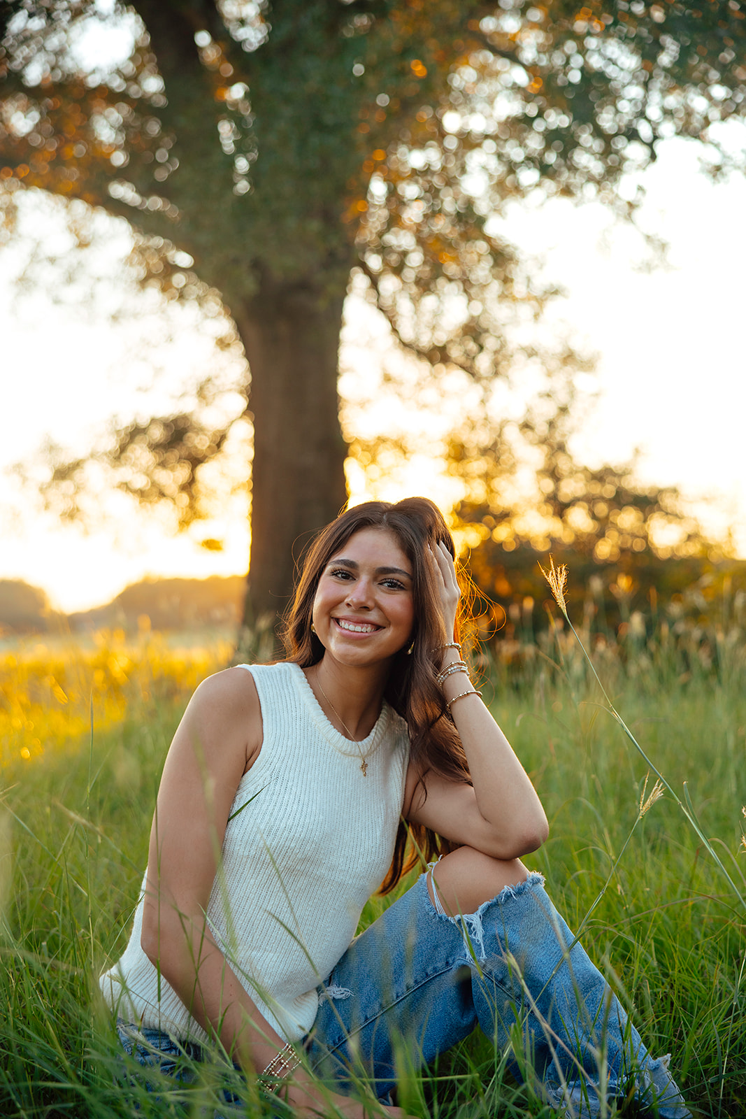high school senior poses in a Texas field during her senior photo session with Kennedi Cooper Photography
