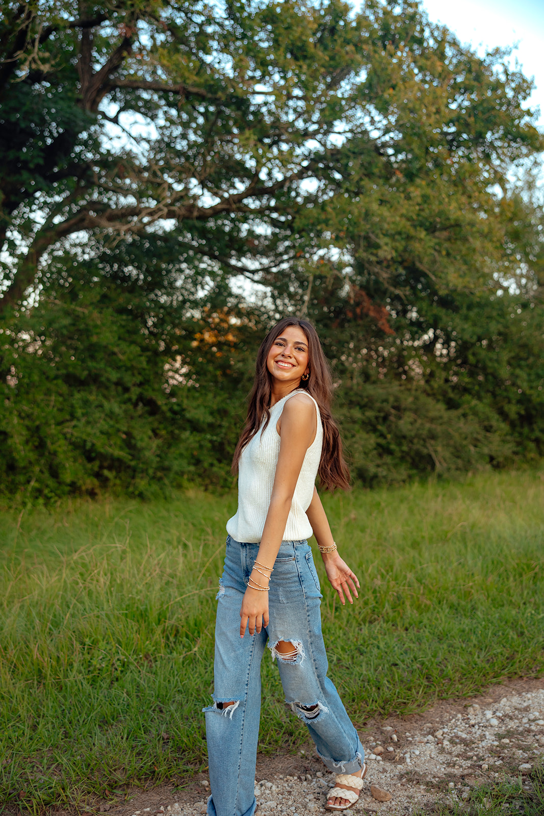 high school senior poses in a Texas field during her senior photo session with Kennedi Cooper Photography